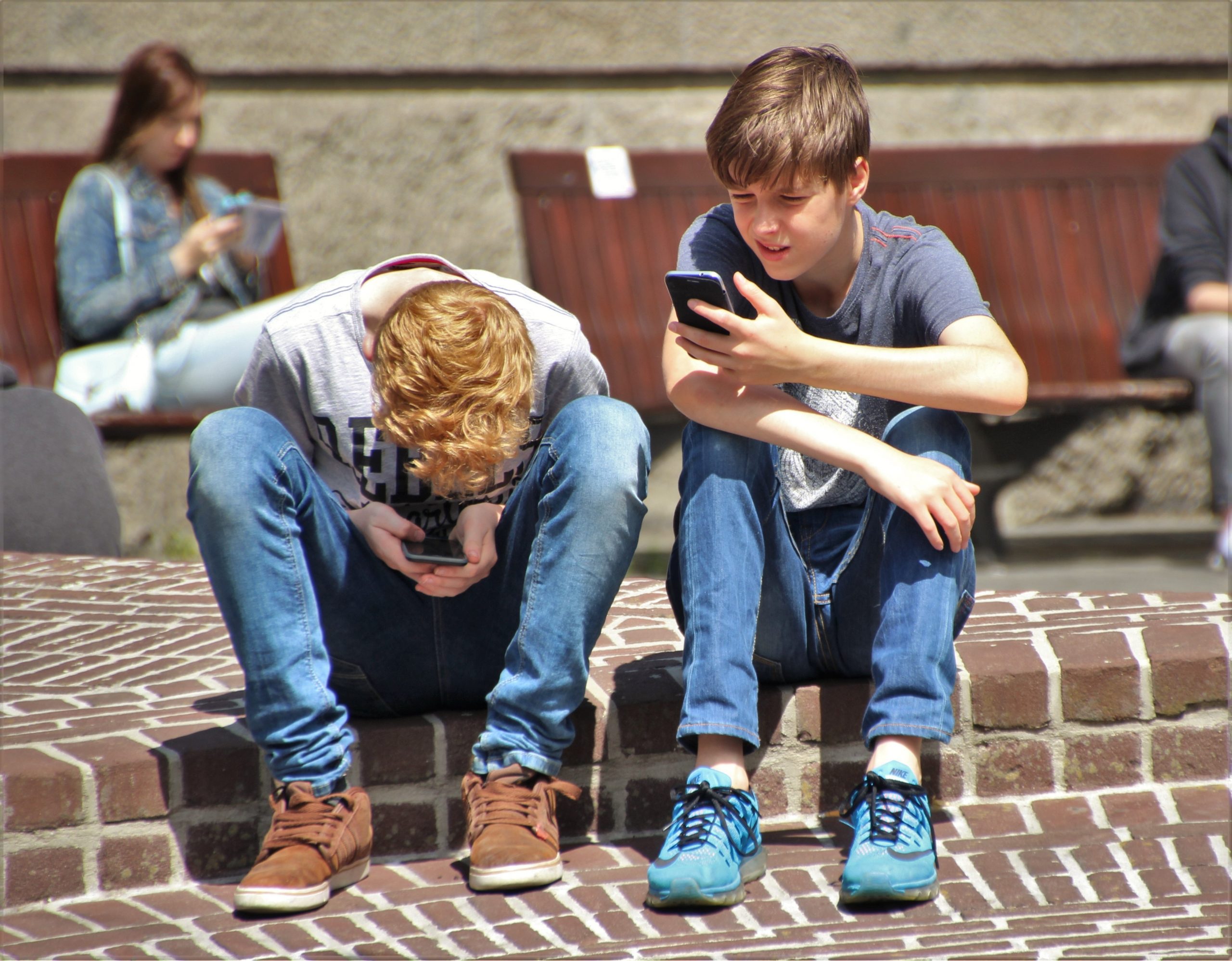 Two boys sitting outside with mobile phones