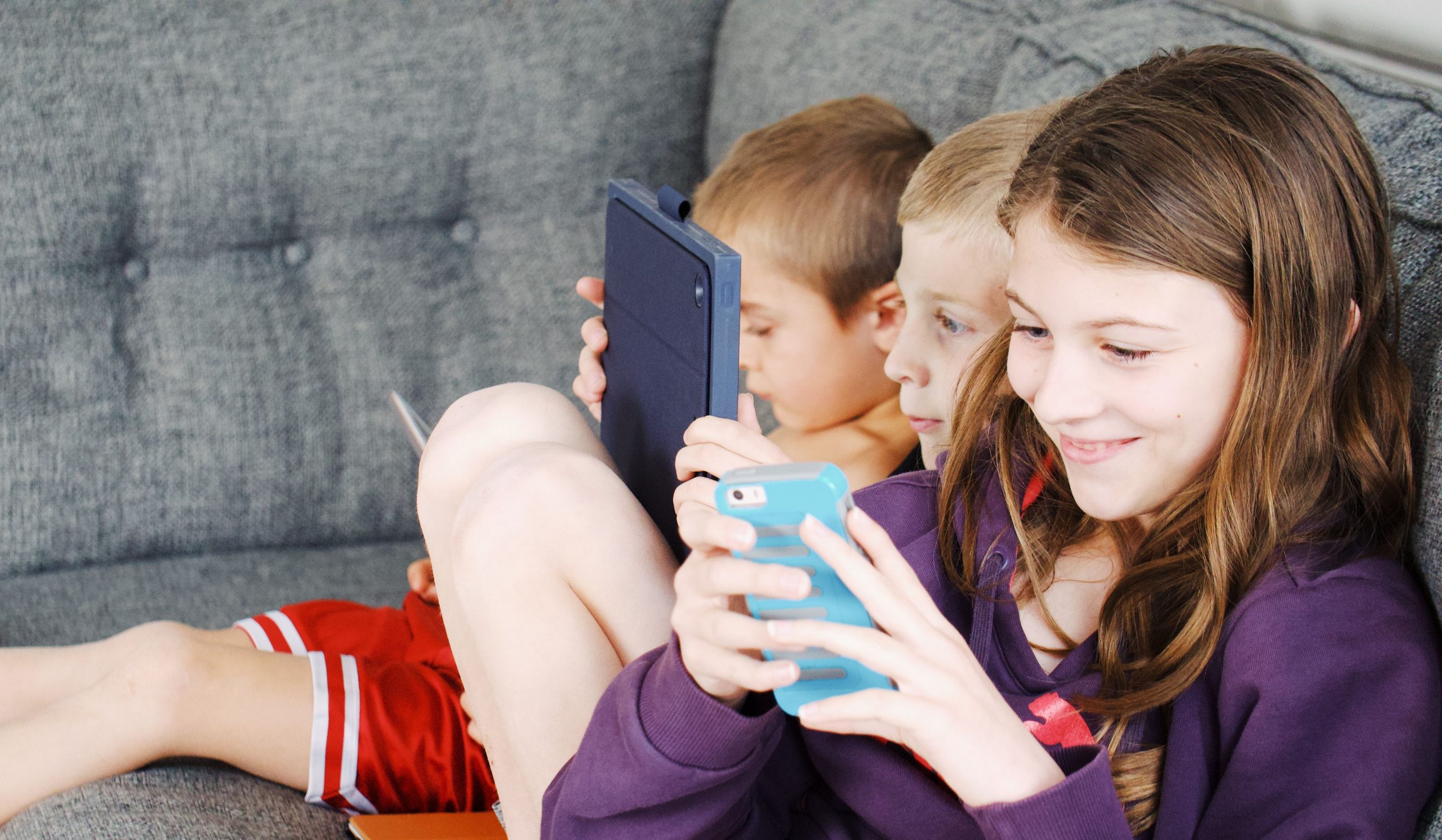 Young children on sofa with mobile phones