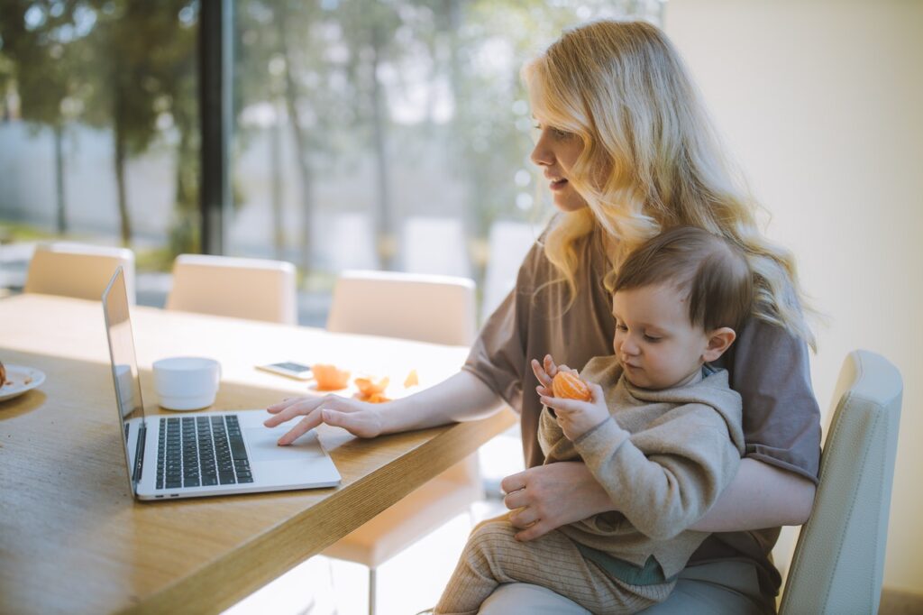 Mother working on laptop with young child on lap