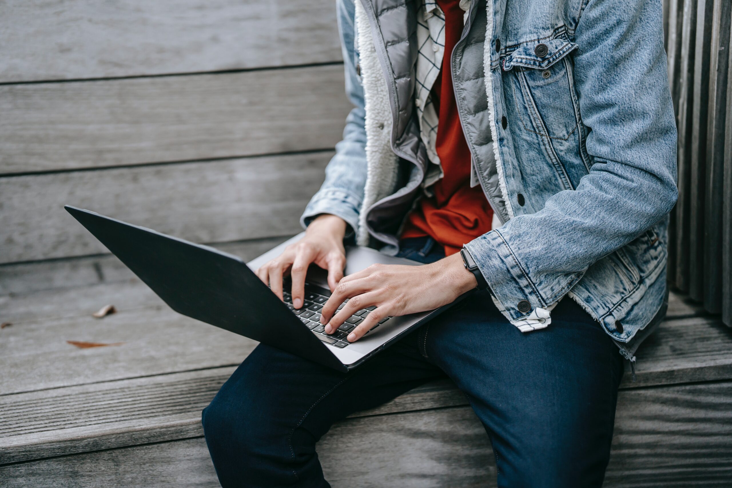 Young person with laptop sitting outside