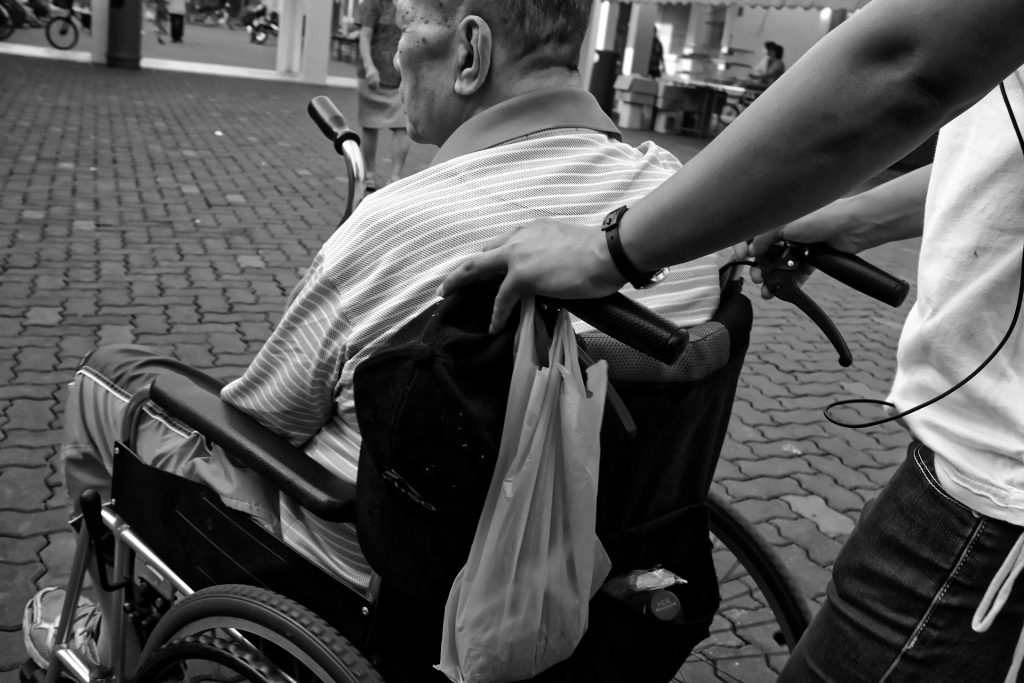 A man in a wheelchair being pushed by another person