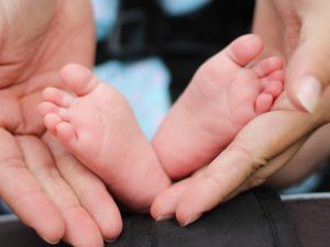 An image showing an adult's hands holding a baby feet