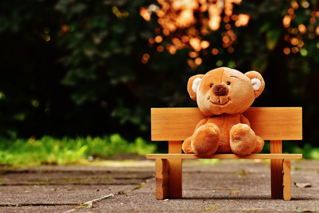 A teddy bear in a bench