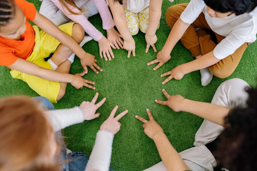 A group of children gathered in a circle and pointing at the middle