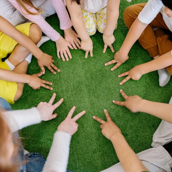A group of children gathered in a circle and pointing at the middle