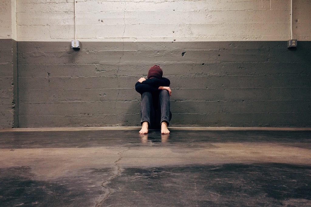 young person sat against a wall